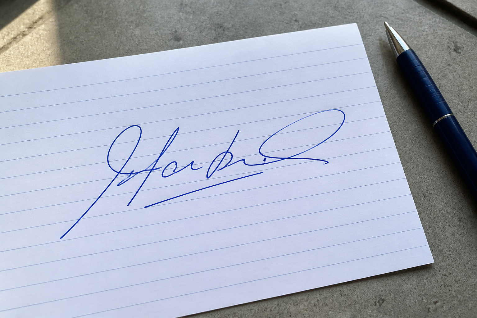 Blue ink handwritten signature photographed on lined paper before background removal